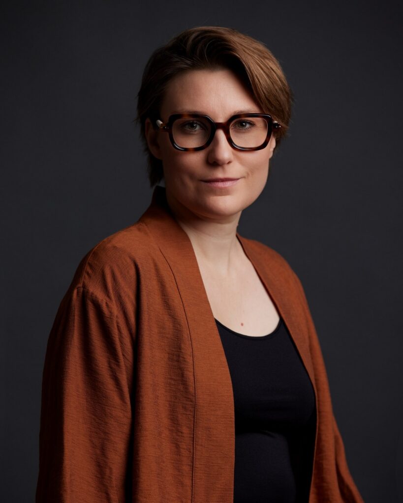 Photographe portrait corporate Le Mans - portrait studio, veste terracotta, fond gris foncé