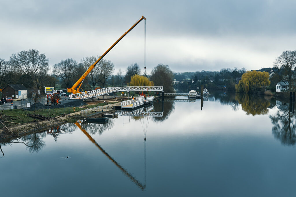 Photographe BTP Sarthe - grue et passerelle aluminium en cours de pose au bord de la Sarthe, reflets sur la rivière, La Suze-sur-Sarthe