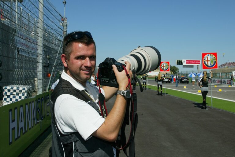 David Piolé, photographe, en bord de piste avec son téléobjectif sur la grille d'un Grand Prix