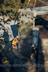 Photographe reportage BTP - deux compagnons ajustant la pose d'un cadre béton, coordination au talkie, chantier du pont de Semallé