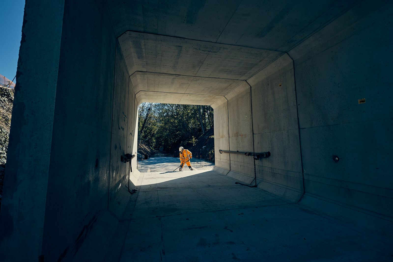 Photographe reportage BTP - ouvrier nettoyant l'intérieur d'un cadre béton préfabriqué à contre-jour, chantier du pont de Semallé (Orne)