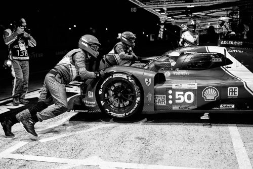 Arrêt aux stands en pleine nuit pendant les 24 Heures du Mans, mécaniciens poussant une Ferrari Hypercar n°50